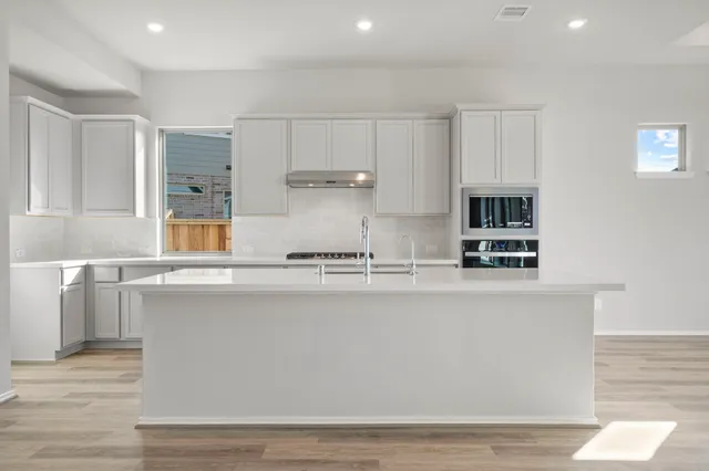 a kitchen with stainless steel appliances granite countertop a sink a stove and a refrigerator