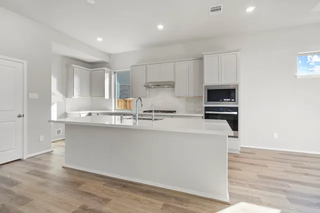 a kitchen with stainless steel appliances a stove a sink and white cabinets