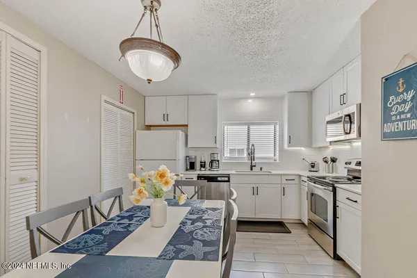 a kitchen with stainless steel appliances granite countertop a sink dishwasher a stove a refrigerator and white cabinets with wooden floor