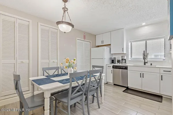 a kitchen with white cabinets and wooden floor