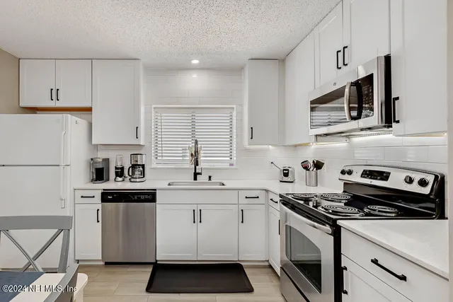 a kitchen with stainless steel appliances a sink stove and white cabinets