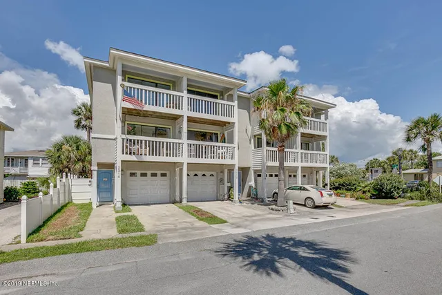 a view of a brick house with potted plants and a yard
