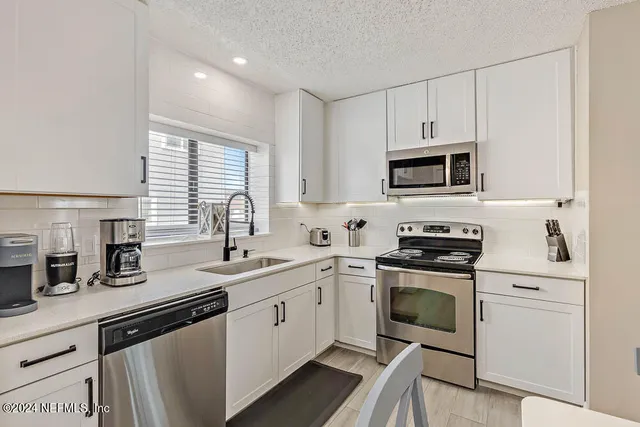 a kitchen with appliances a sink and cabinets