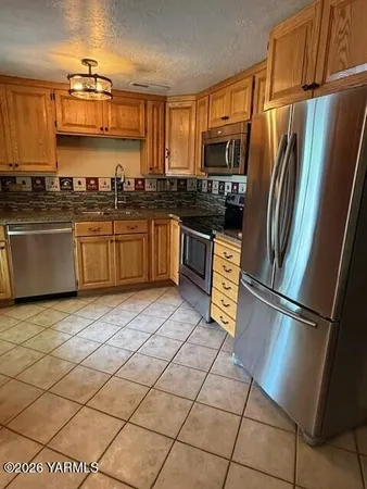 a kitchen with stainless steel appliances granite countertop a refrigerator a stove a sink and a microwave