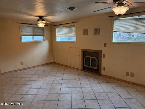 a view of an empty room with a fireplace and a window