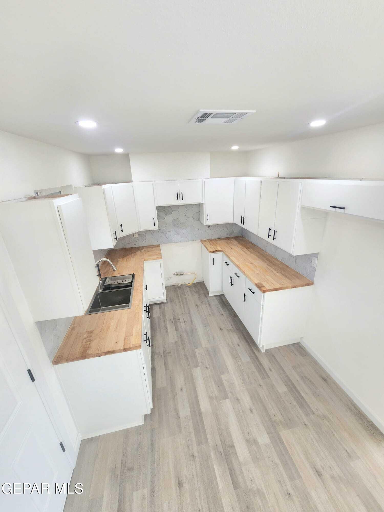 5845 Threadgill Avenue El Paso, TX 79924 - Photo 10 of 50 a large white kitchen with wooden floors and stainless steel appliances