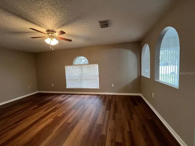a view of an empty room with a window and wooden floor