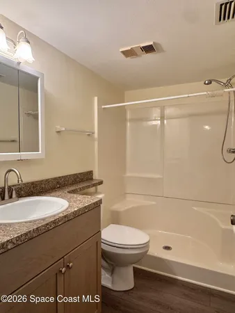 a bathroom with a granite countertop sink toilet a mirror and shower