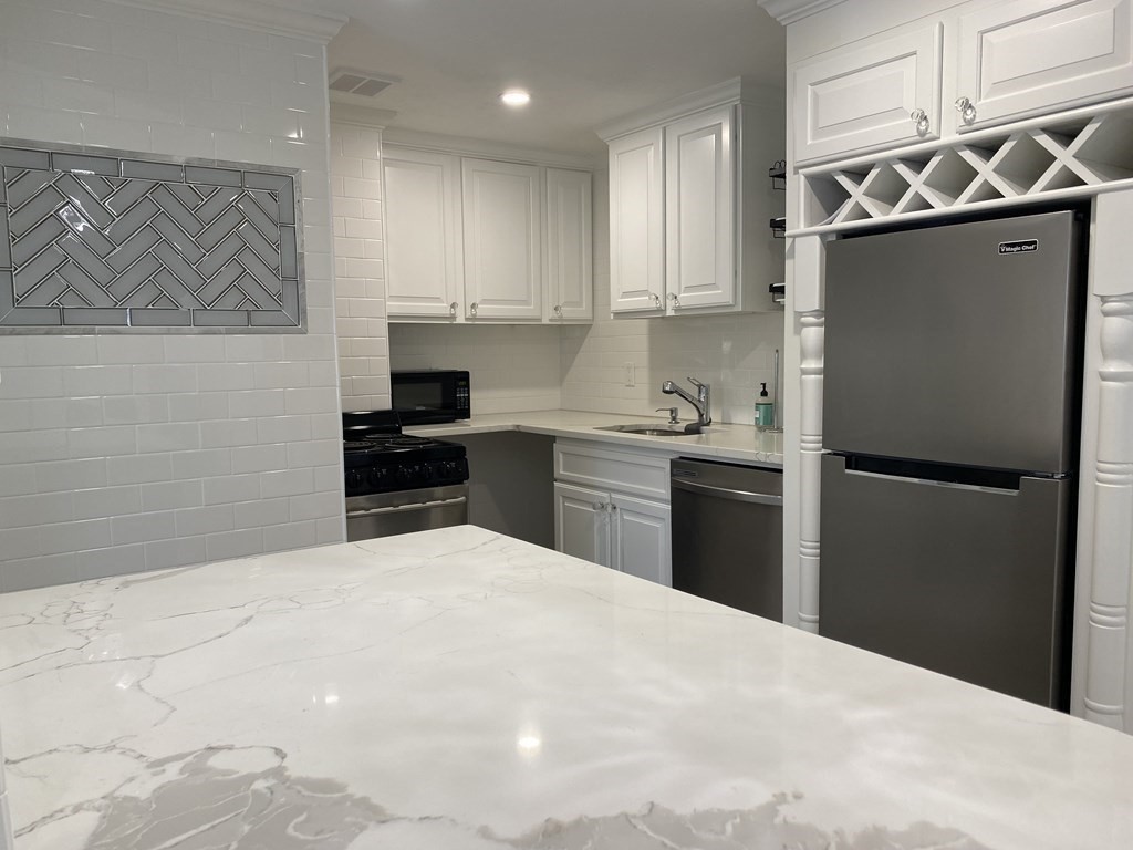 210 Hillside Avenue, Unit 37 Needham, MA 02494 - Photo 3 of 14 a kitchen with granite countertop a refrigerator stove and sink