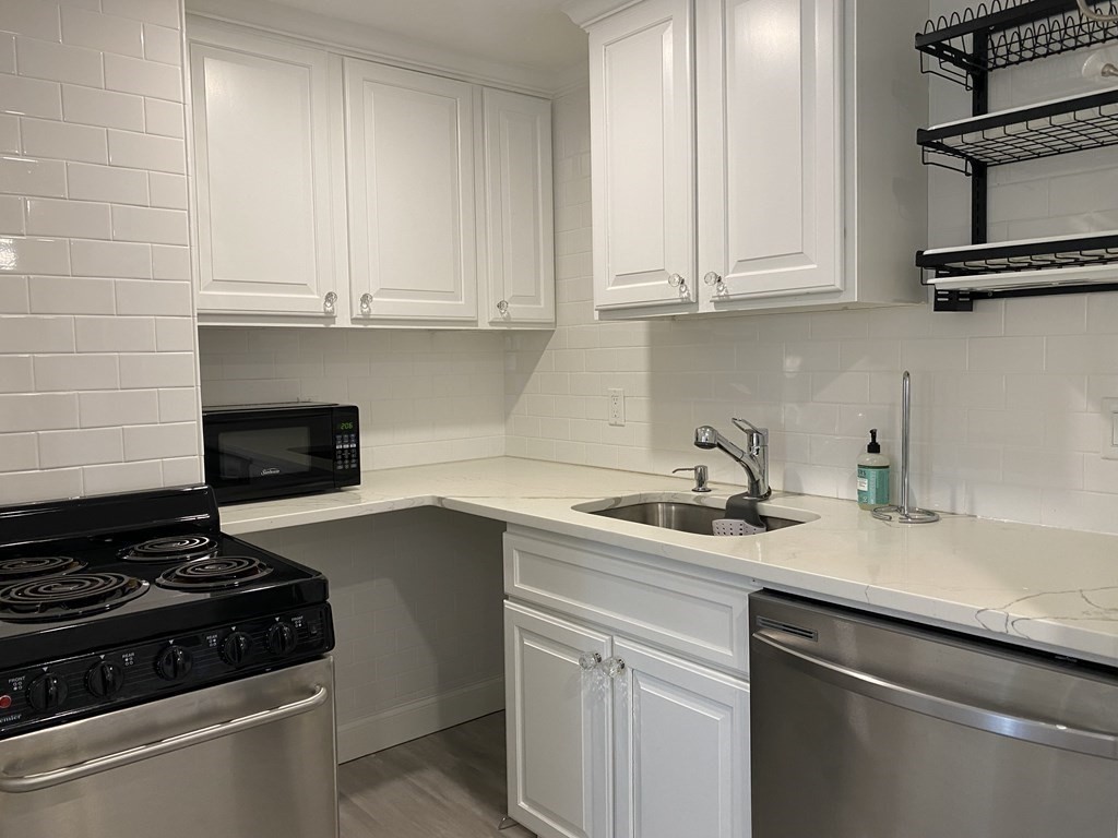 210 Hillside Avenue, Unit 37 Needham, MA 02494 - Photo 7 of 14 a kitchen with stainless steel appliances granite countertop white cabinets and a stove a oven with white countertops