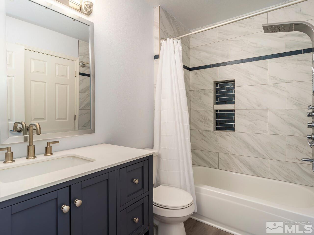 821 University Ridge Drive Reno, NV 89512 - Photo 23 of 28 a bathroom with a sink a mirror a toilet and bathtub