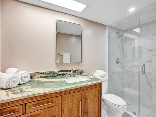 a bathroom with a granite countertop sink a mirror and a toilet
