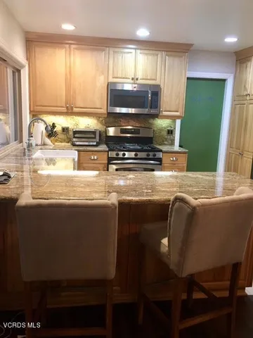 a kitchen with stainless steel appliances granite countertop a table chairs stove refrigerator and cabinets