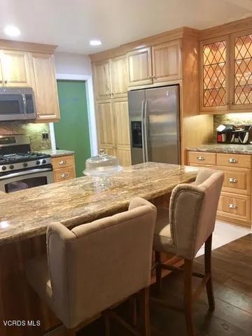 a kitchen with stainless steel appliances granite countertop a refrigerator a stove a sink dishwasher and white cabinets with wooden floor