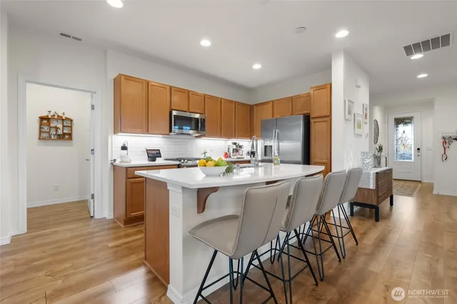 a kitchen with stainless steel appliances granite countertop a table chairs refrigerator and a stove