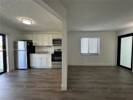 a view of kitchen with stainless steel appliances wooden floor and window