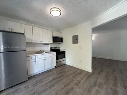 a kitchen with granite countertop a refrigerator stove top oven and sink