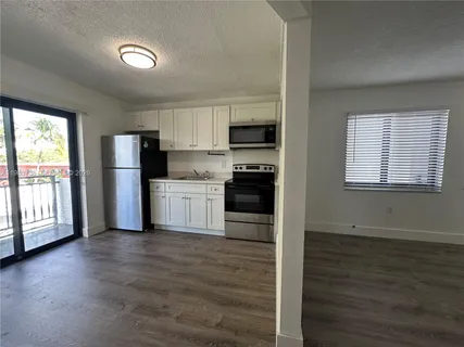 a kitchen with stainless steel appliances granite countertop a stove top oven a sink and a refrigerator