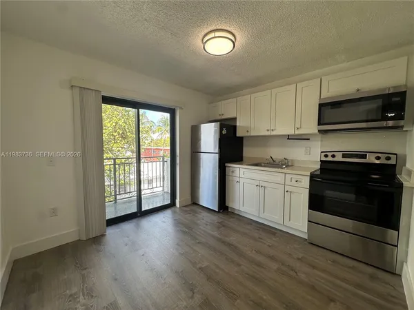a kitchen with a white cabinets and wooden floor