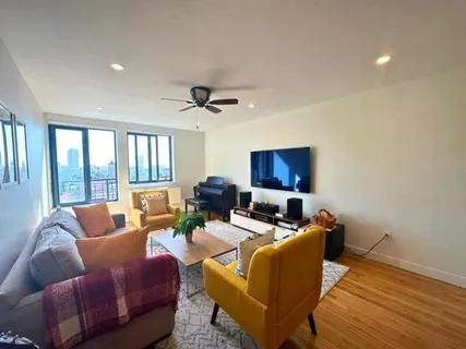 a living room with furniture a ceiling fan a flat screen tv and a window