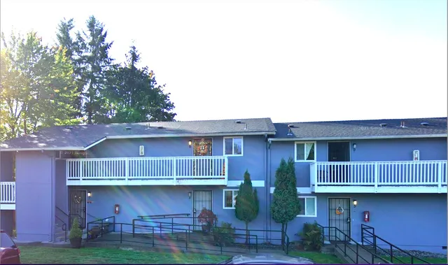 a view of house with wooden fence and large trees