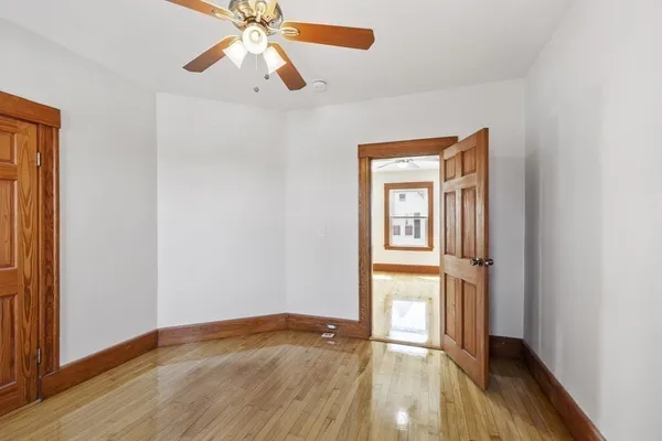 a view of empty room with wooden floor and fan