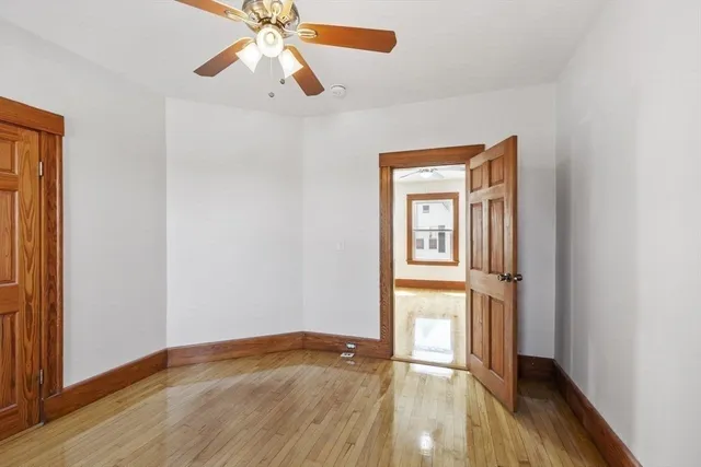 a view of empty room with wooden floor and fan