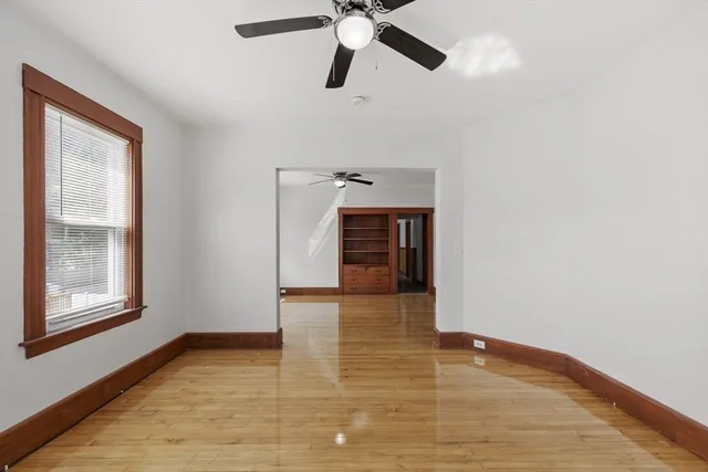 a view of empty room with wooden floor and ceiling fan