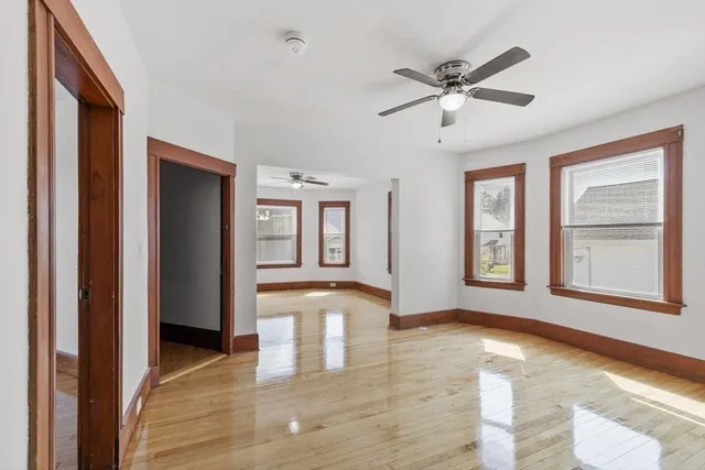 a view of an empty room with window and wooden floor