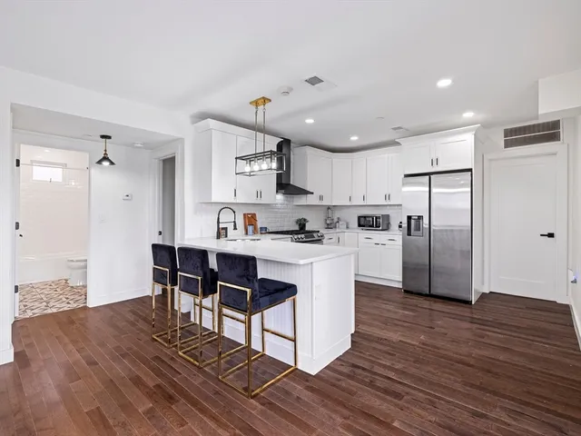 a kitchen with stainless steel appliances kitchen island granite countertop a table chairs microwave and sink