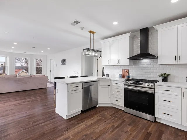 a kitchen with white cabinets stainless steel appliances and a refrigerator