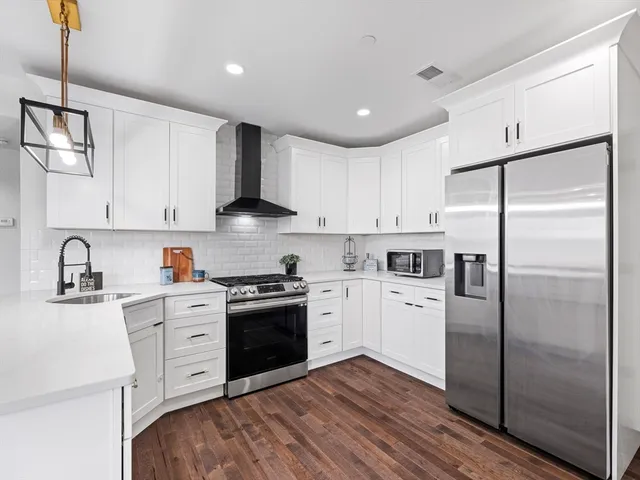 a kitchen with stainless steel appliances granite countertop a refrigerator and a stove top oven