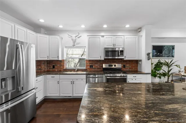 a kitchen with kitchen island granite countertop a stove a sink and a microwave