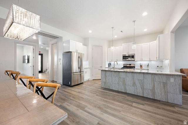 4281 Canterbury Road Hurricane, UT 84737 - Photo 4 of 24 Open-concept kitchen and dining area featuring wood-finish flooring, white cabinetry, stainless steel appliances, a center island with pendant lighting, and recessed lighting
