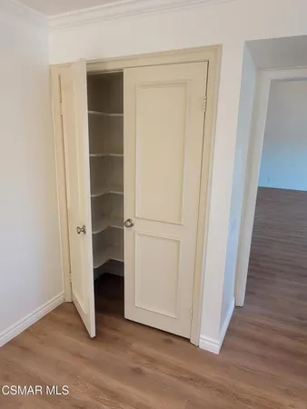 a view of an empty room with wooden floor and closet