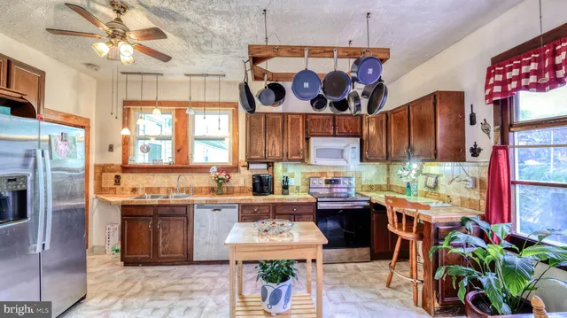 a kitchen with stainless steel appliances granite countertop a refrigerator and a dining table