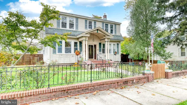 a view of a brick house with a small yard and large trees