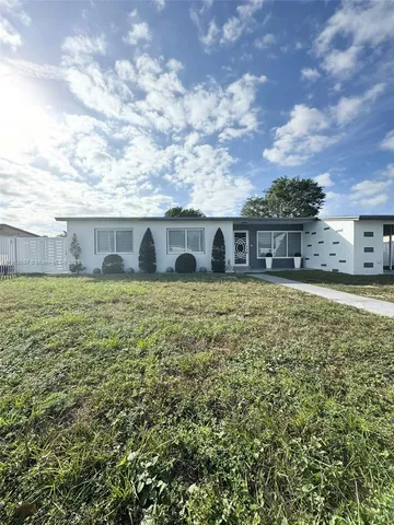 a view of a house with a big yard and large trees