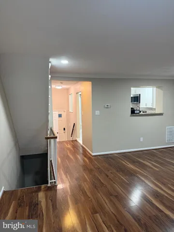 a view of an empty room with wooden floor and stairs