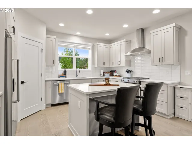 a kitchen with stainless steel appliances kitchen island granite countertop a table chairs sink and cabinets