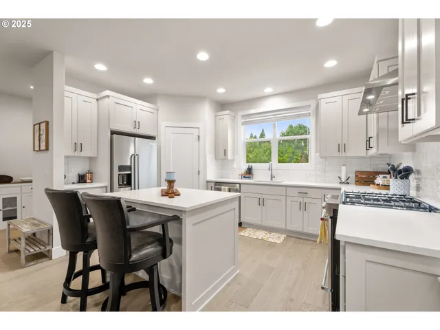 a kitchen with stainless steel appliances kitchen island wooden cabinets and white table