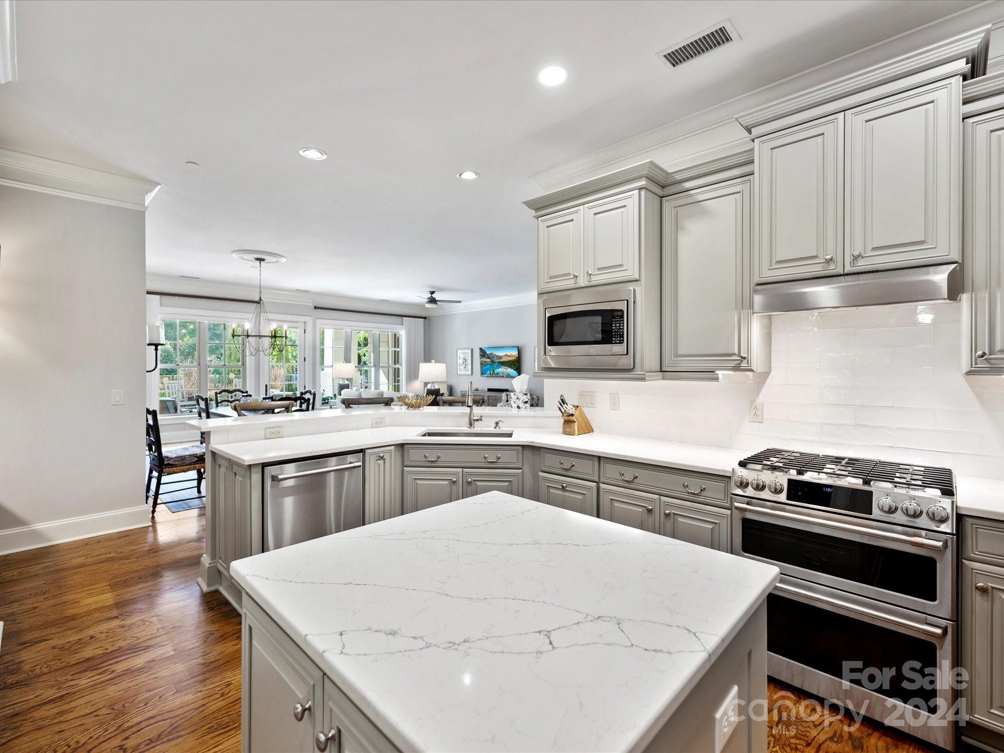2823 Providence Road, Unit 216 Charlotte, NC 28211 - Photo 16 of 35 a kitchen with kitchen island white cabinets appliances and wooden floor