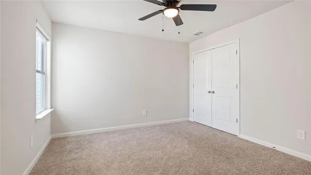 an empty room with a ceiling fan and a window