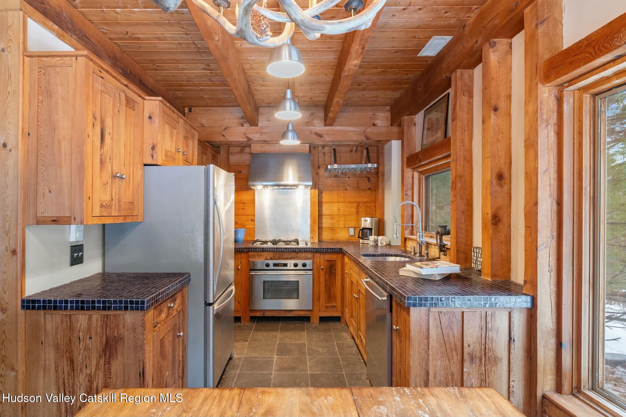 250 Macdaniel Road Woodstock, NY 12498 - Photo 15 of 39 a kitchen with stainless steel appliances granite countertop a stove a refrigerator a sink dishwasher and wooden cabinets with wooden floor