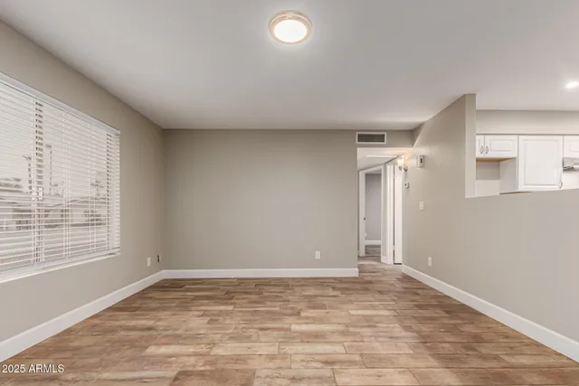 a view of empty room with wooden floor and fan
