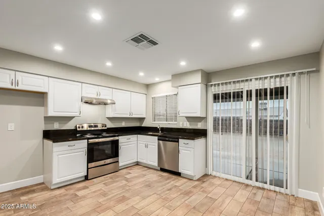 a kitchen with stainless steel appliances granite countertop a stove sink and cabinets