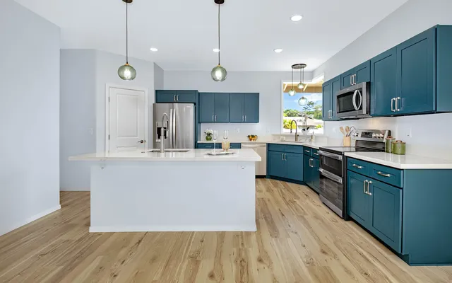 a large kitchen with stainless steel appliances granite countertop a stove a sink dishwasher a microwave oven and a cabinets with wooden floor