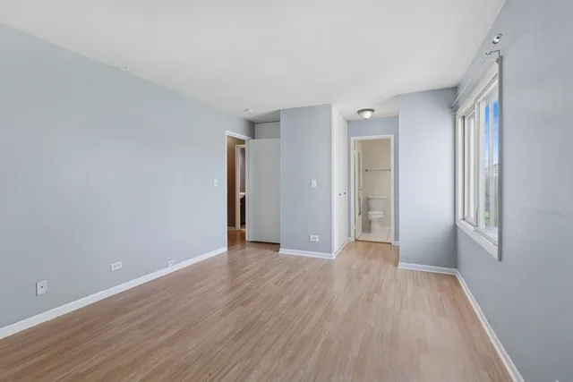a view of an empty room with closet and a window