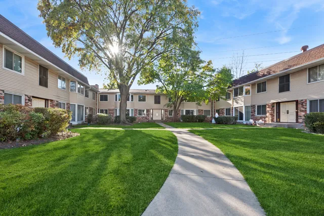 a view of a front of residential houses with yard and green space