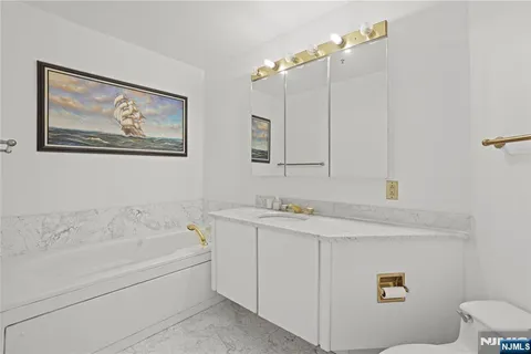 a bathroom with a granite countertop sink a toilet a mirror and shower